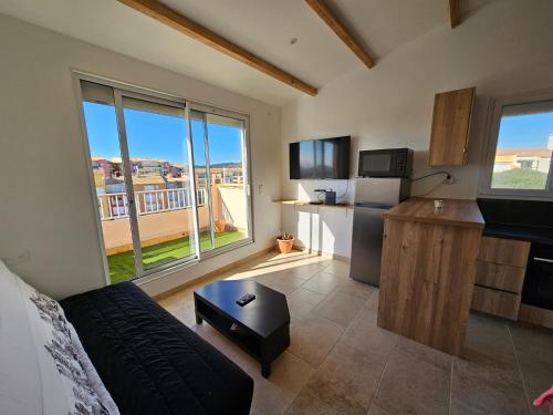 un salon avec une cuisine et une grande fenêtre dans l'établissement Appartement cap d'agde, au Cap d'Agde