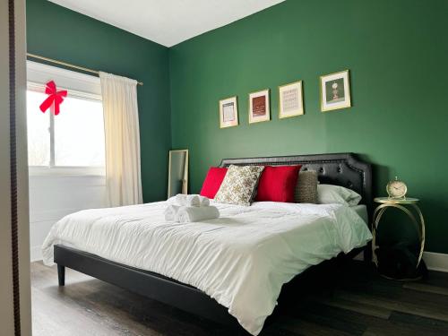 a green bedroom with a bed with red pillows at Evansville Holiday House in Evansville
