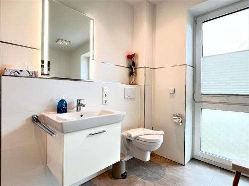 une salle de bain avec un lavabo, des toilettes et un miroir dans l'établissement Haus Undine, Deichhörn 6a, à Dangast