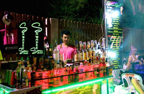 a man standing behind a bar with lots of bottles at Rocking Chair Pool Villa in Chaweng