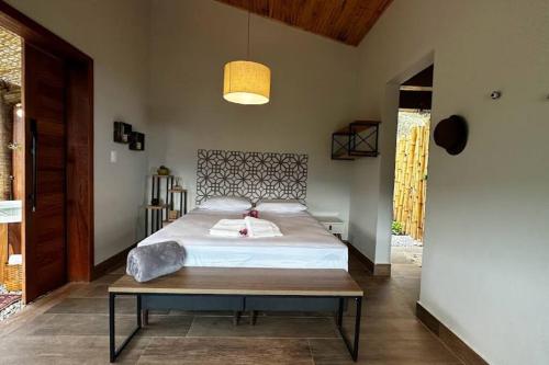a bedroom with a large bed and a table at Cabanas da Mata - Cabana Flamboyant - Casa Branca in Brumadinho