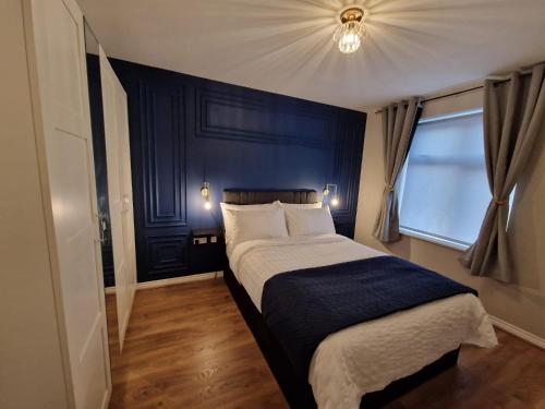 a bedroom with a bed with a blue wall at Impeccable 2-Bed Apartment in Newcastle upon Tyne in Newcastle upon Tyne