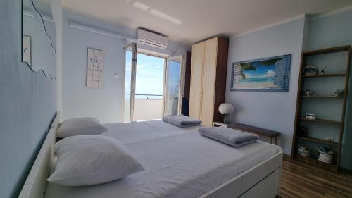 a bedroom with a bed with pillows and a window at Apartment with direct Sea View, Free Parking and close to Beaches and Promenade in Lovran
