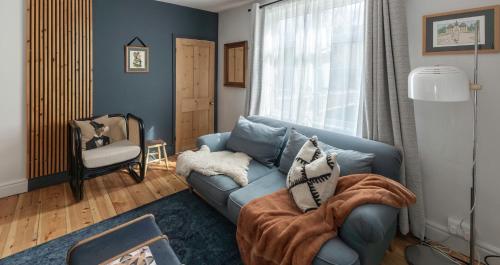 a living room with a blue couch and a chair at Bijou cottage in a super location… ! in Sileby