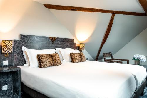 une chambre avec un grand lit blanc avec des oreillers dans l'établissement Pavillon Opéra Grands Boulevards, à Paris