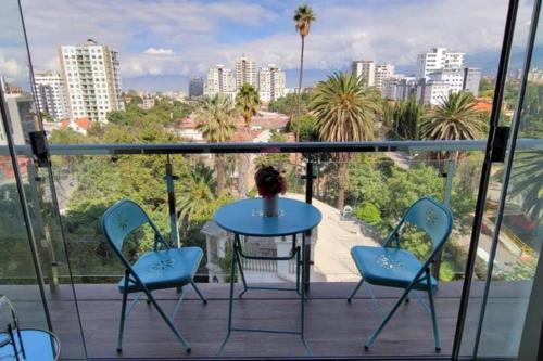 a table and chairs on a balcony with a view of a city at Hermoso departamento sobre Av. America cerca al Sombrero de Chola in Cochabamba