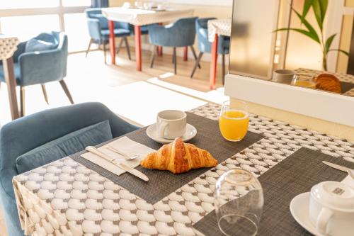 a table with a breakfast of croissants and orange juice at Hôtel de la Mairie in Saint-Pol-de-Léon