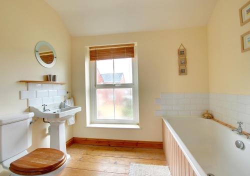 baño con bañera, lavabo y ventana en Avocet Cottage, en Dersingham