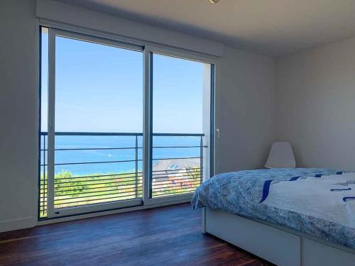 サン・ポル・ド・レオンにあるVilla Nord Finistère 5 étoilesのベッドと大きな窓のある寝室