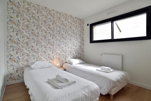 zwei Einzelbetten in einem Zimmer mit Fenster in der Unterkunft Villa Armor Glaz - Maison avec jacuzzi in Saint-Cast-le-Guildo