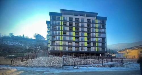 un gran edificio de apartamentos con ventanas amarillas y nieve en Apartman M&M en Travnik