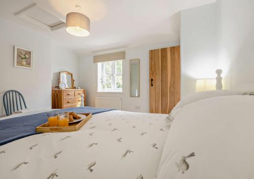 Schlafzimmer mit einem Bett und einem Tablett mit Orangensaft in der Unterkunft Bay Tree Cottage - Dersingham in Dersingham