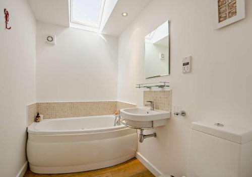 ein weißes Badezimmer mit einem Waschbecken, einer Badewanne und einem Spiegel in der Unterkunft Bay Tree Cottage - Dersingham in Dersingham