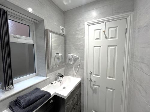 a white bathroom with a sink and a mirror at Melbury Rooms & Studios in Exeter