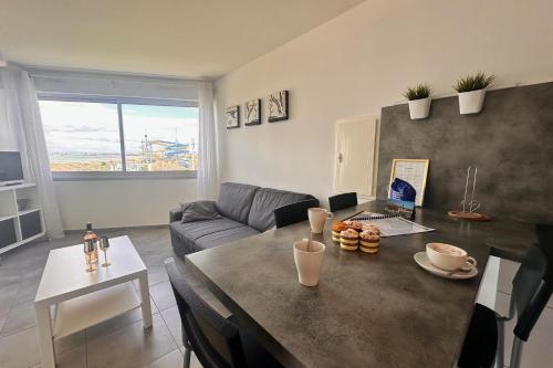 un salon avec une table et un canapé dans l'établissement Le Soleil Couchant Studio Vue Mer, au Grau-du-Roi