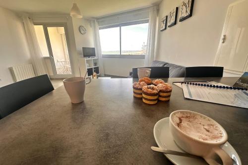- une table avec une tasse de café et des beignets dans l'établissement Le Soleil Couchant Studio Vue Mer, au Grau-du-Roi