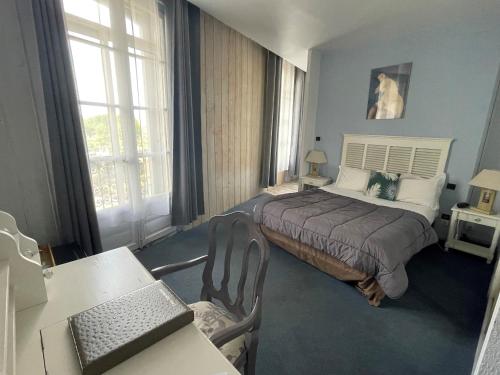 Hotel De France في بيربينيا: غرفة نوم مع سرير ومكتب مع الكمبيوتر المحمول