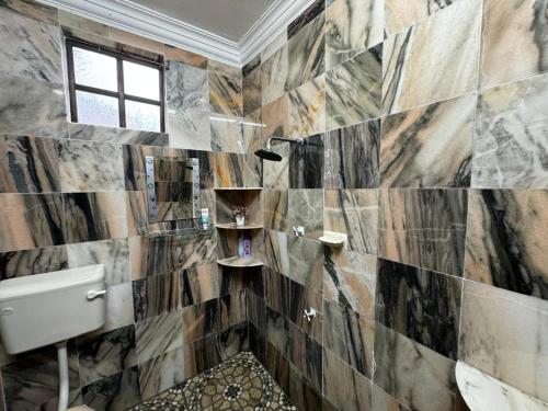 Kampung Bota Kiri的住宿－Marbel Villa，浴室设有黑色和棕色的瓷砖墙。