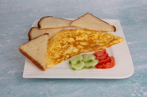 a white plate with an egg and toast and vegetables at ALYA Hotel in Barka