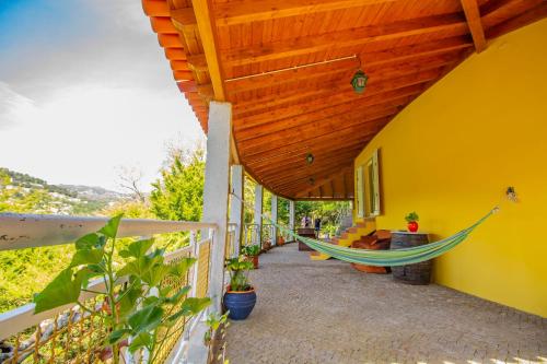 a porch with a hammock on a yellow building at Quinta de São Francisco in Cinfães