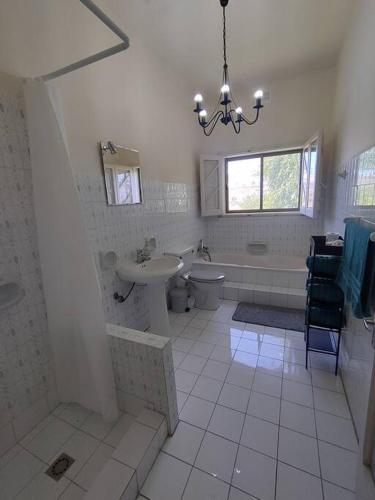 a bathroom with a sink and a toilet and a chandelier at Wilga Summit Apartment C in Qala