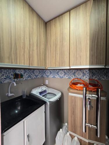 a small kitchen with a washing machine and wooden cabinets at Casa Rosa in Cuiabá