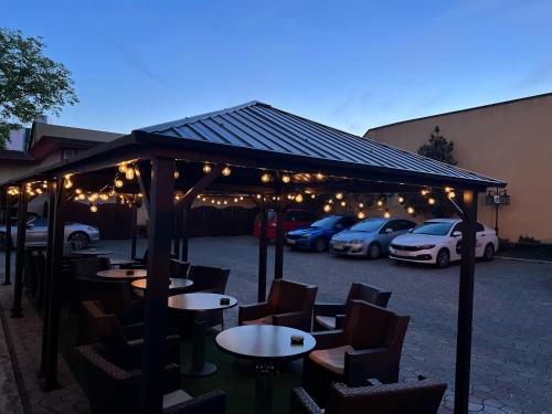 a group of tables and chairs under a pavilion with parked cars at Ambassador Hotel in Timişoara