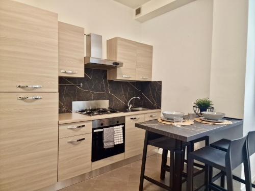 una cucina con fornelli e un tavolo con sedie di Al Centro del Centro Apartment by TraMonti a L'Aquila