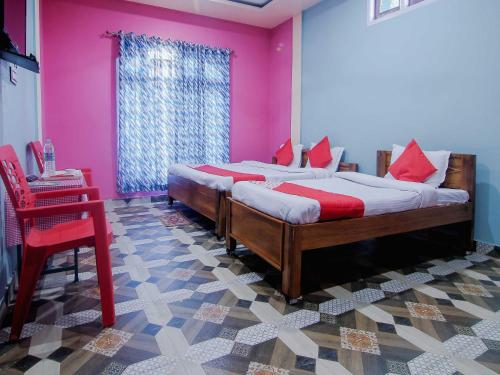 a bedroom with two beds and a pink wall at OYO Flagship Bonfire Kaziranga Resort in Kāziranga