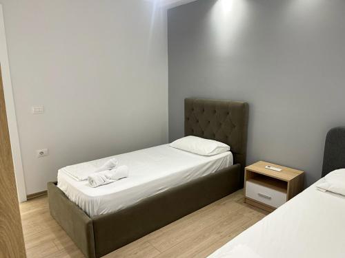 - une petite chambre avec 2 lits et une table de nuit dans l'établissement New Bazaar 2022, à Tirana