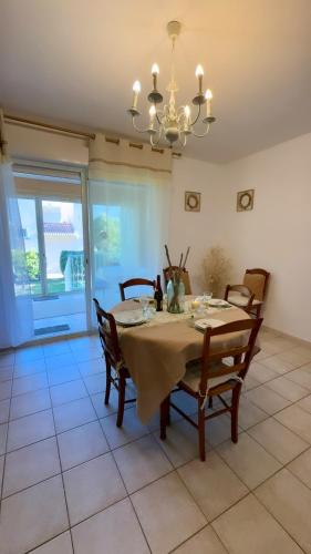 une salle à manger avec une table, des chaises et un lustre dans l'établissement Maison en bord de mer, Plage de la Marana en Corse, à Borgo