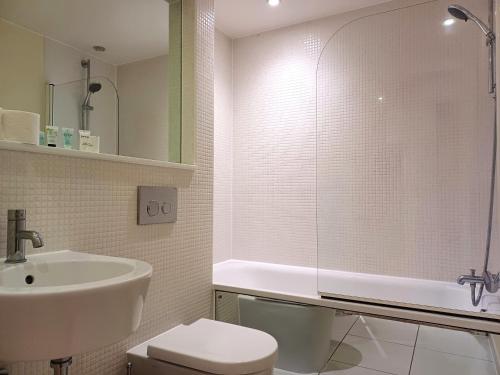 a bathroom with a sink and a tub and a toilet at Canary Wharf Serviced Apartments in London