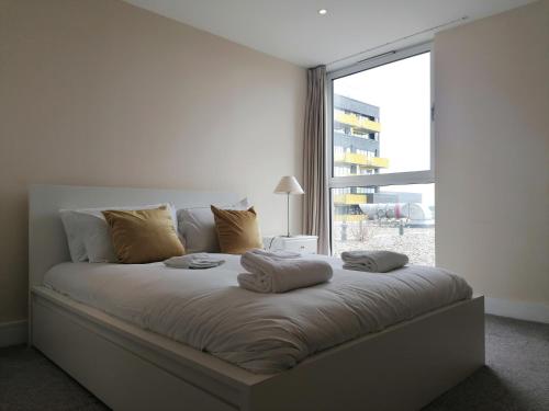 a bedroom with a large bed with a large window at Canary Wharf Serviced Apartments in London