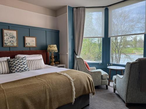 a bedroom with a bed and two chairs and a window at Mill on the Exe in Exeter