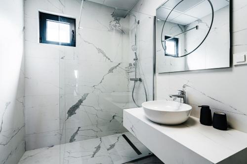 a white bathroom with a sink and a mirror at Monte Living by In Property in Ðenaši