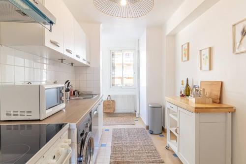 une cuisine blanche avec un évier et un micro-ondes dans l'établissement Spacious T3 Near The Beach And Station Roquebrune, à Roquebrune-Cap-Martin