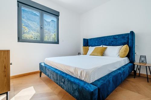 a blue bed in a white room with a window at Monte Living by In Property in Ðenaši