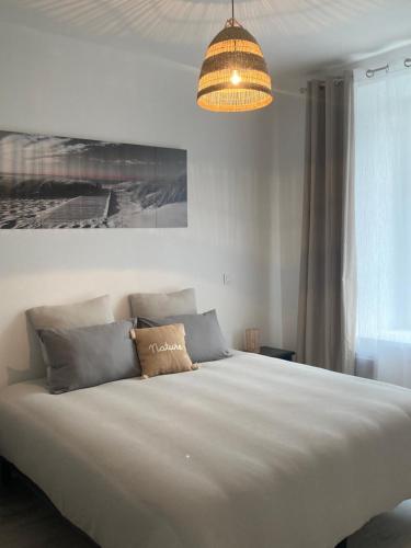 een slaapkamer met een groot wit bed en een kroonluchter bij La petite fermette in Saint-Maur