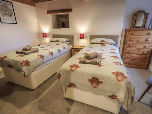 two twin beds in a bedroom with a dresser at Boskins in Sedbergh