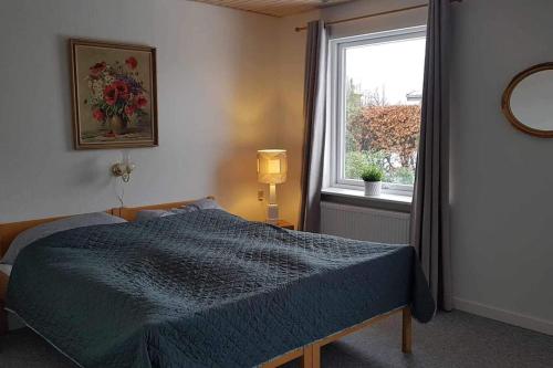 um quarto com uma cama azul e uma janela em Feriehus i Sæby nær by, skov og strand em Sæby