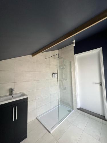 a shower with a glass door in a bathroom at House Next to the Station in Watford