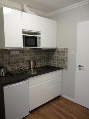 a white kitchen with a sink and a microwave at ILLA Apartments in Eger