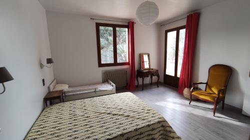 Schlafzimmer mit einem Bett, einem Stuhl und Fenstern in der Unterkunft Maison de vacances avec piscine et jardin in Bompas
