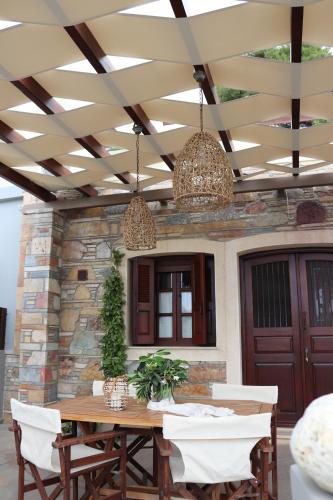 a patio with a wooden table with white chairs at OSTRIA BOUTIQUE HOME in Kalymnos