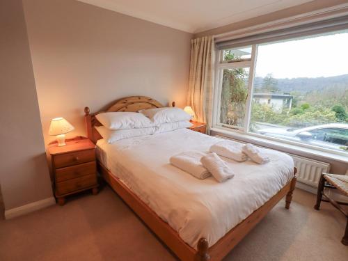 a bedroom with a bed with two pillows and a window at Tanna Hill in Bowness-on-Windermere