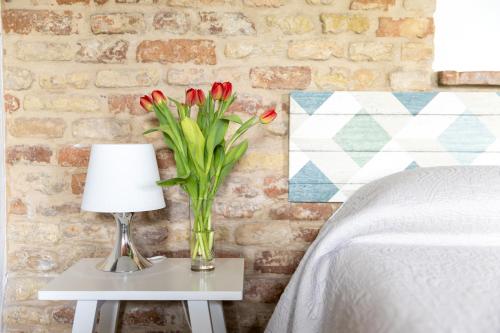 un vase de tulipes rouges sur une table avec une lampe dans l'établissement B&B Casa Fanny Riviera Del Conero, à Loreto