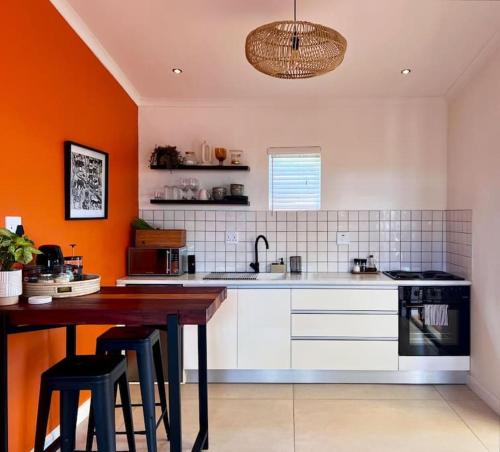 a kitchen with orange walls and a wooden table at Garden Oasis in Windhoek