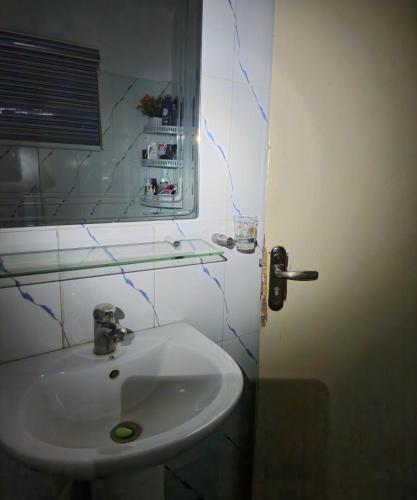 uma casa de banho com um lavatório branco e um espelho. em Quiet and comfortable home em Lagos