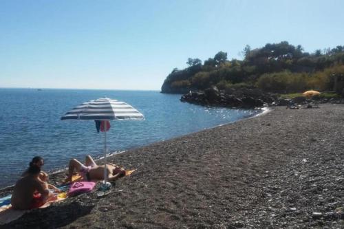 a group of people sitting on a beach with an umbrella at Domus Mea Monolocale in Trabia