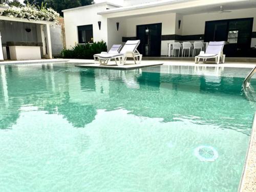 basen z niebieską wodą i białymi krzesłami w obiekcie La villa de Michel w mieście Ngaparou
